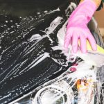 A person cleaning a car with soapy water